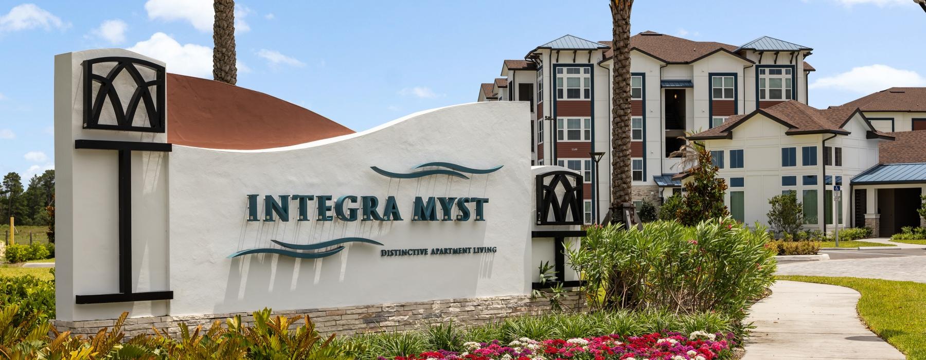 a building with palm trees and a sign in front of it